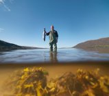 Fisherman wading in loch with freshly caught salmon — Stock Photo