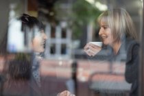 Mulheres sorridentes tomando café no café — Fotografia de Stock