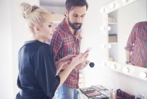 Male make up artist and model looking at smartphone before photo shoot — Stock Photo