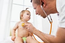 Médico examinando menina criança com estetoscópio — Fotografia de Stock
