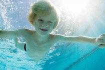 Усміхнений хлопчик плаває в басейні — стокове фото