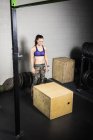 Молодая женщина тренируется, готовится прыгнуть на ящик в спортзале — стоковое фото
