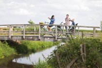 Ciclismo familiar sobre puente de madera - foto de stock