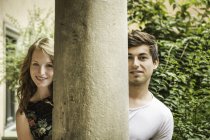 Giovane coppia guardando intorno pilastro — Foto stock
