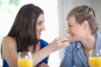 Woman feeding girlfriend breakfast — Stock Photo