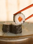 Chopsticks holding sushi — Stock Photo
