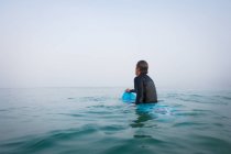 Человек, сидящий на доске для серфинга в океанской воде — стоковое фото