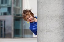 Boy peering out from behind column — Stock Photo