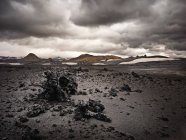 Roches de lave sur le terrain avec ciel nuageux sombre — Photo de stock