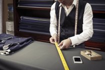 Tailor taking measurements from ruler in tailors shop — Stock Photo