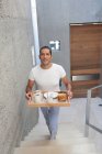 Uomo che porta vassoio di cibo su per le scale — Foto stock