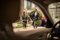 Car window view of businesswoman and man walking outside hotel, Dubai, United Arab Emirates — Stock Photo