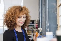 Femme dans l'atelier de couture regardant vers le bas souriant — Photo de stock