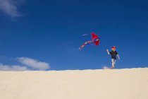Menino voando pipa na duna de areia — Fotografia de Stock