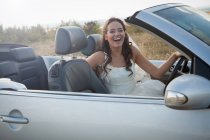 Newlywed bride sitting in convertible — Stock Photo