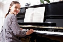 Ragazza sorridente che si esercita al pianoforte, concentrarsi sul primo piano — Foto stock