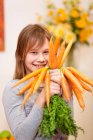 Улыбающаяся девушка с кучей моркови — стоковое фото