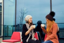 Dos mujeres adultas jóvenes disfrutando del café en la terraza de la azotea - foto de stock