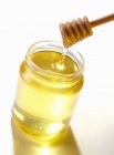 Мішалка над баночкою меду на білому тлі — стокове фото