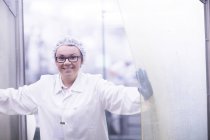 Factory worker wearing hair net looking at camera smiling — Stock Photo