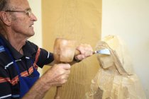 Скульптор вырезает фигурку из дерева — стоковое фото