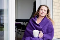 Woman with coffee in blanket outdoors — Stock Photo