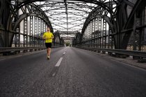 Giovane atleta di sesso maschile che corre sul ponte — Foto stock