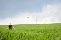 Беременная женщина, идущая по ветряной электростанции — стоковое фото