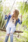 Glückliche junge Frau schaukelt auf Gartenschaukel — Stockfoto