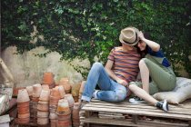 Молода пара сидить на дерев'яних палітрах в саду — стокове фото