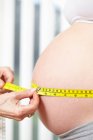 Mains mesurant ventre enceinte — Photo de stock