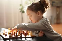 Menina jogando xadrez dentro de casa, foco seletivo — Fotografia de Stock