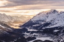 Snowcapped rocky mountains under cloudy sunset sky — Stock Photo