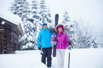 Casal carregando esquis e postes na neve — Fotografia de Stock