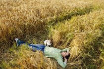 Homme avec chien couché dans un champ de blé — Photo de stock