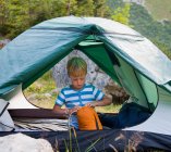 Boy unpacking sleeping bag in tent — Stock Photo