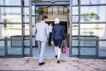 Rear view of businessmen and woman arriving at office building — Stock Photo