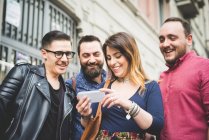 Gruppe von Freunden schaut sich gemeinsam Nachricht auf Handy an — Stockfoto
