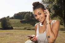 Young woman listening to mp3 player in park — Stock Photo