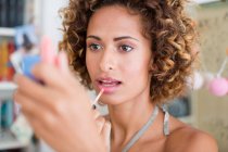 Woman applying make up in mirror — Stock Photo