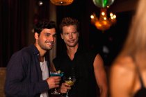 Улыбающиеся мужчины, пьющие коктейли в клубе — стоковое фото