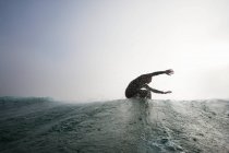 Человек в купальнике, серфинг на океанской волне, бухта сисек, Корнуолл, Англия — стоковое фото