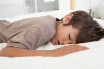 Boy sleeping on bed, focus on foreground — Stock Photo