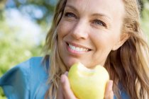 Жінка їсть яблуко і посміхається — стокове фото