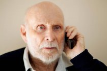 Older man talking on cell phone, focus on foreground — Stock Photo
