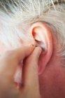 Older person inserting hearing aid — Stock Photo