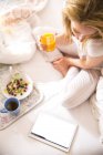 Overhead view of young woman on bed reading digital tablet in morning — Stock Photo