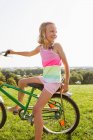 Девушка сидит на велосипеде в траве — стоковое фото
