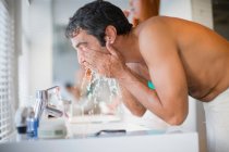Homme se laver le visage dans la salle de bain — Photo de stock