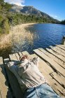 Uomo sdraiato sul molo al lago — Foto stock